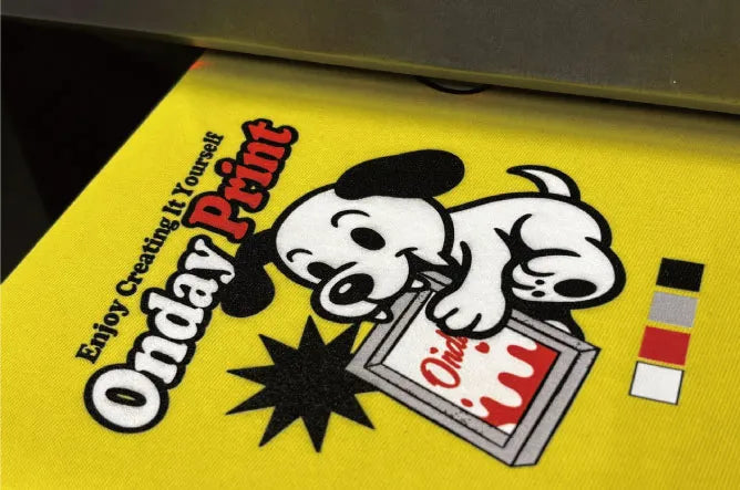 インクジェットプリントの仕上がりを接写した画像。黄色Tシャツにフルカラーのキャラクターデザインが印刷されており、グラデーションと色域の広さを示している