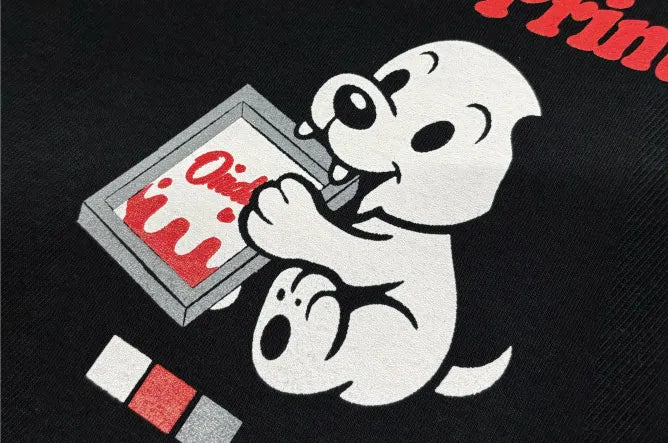 シルクスクリーンプリントの仕上がりを接写した画像。黒Tシャツに白・グレー・赤の多色刷りでキャラクターが鮮明に再現されており、発色の鮮やかさとエッジの鋭さを示している